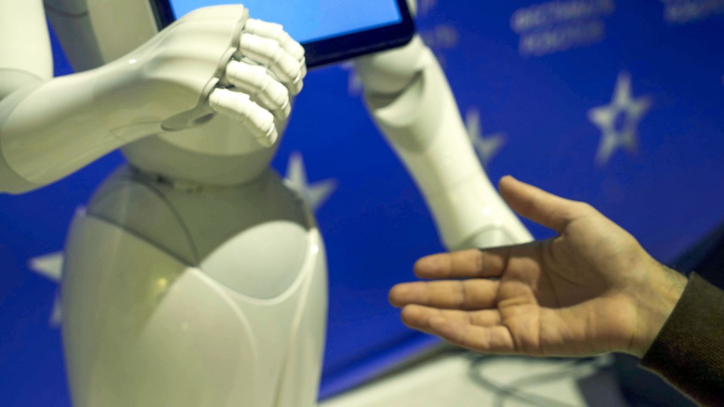 Symbolbild: Ein Roboter und ein Mensch reichen sich die Hände