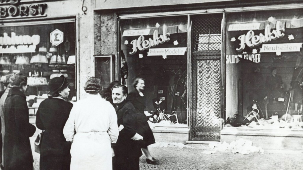 Passanten stehen im November 1938 in einer Stadt in Deutschland vor einem jüdischen Geschäft, dessen Schaufensterscheiben am 9.11.1938 zerstört wurden.