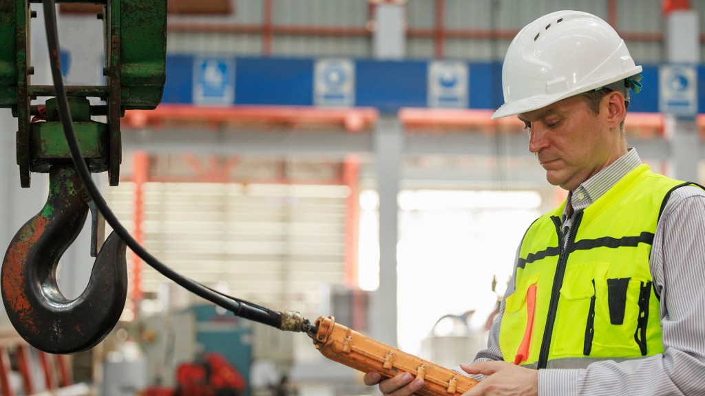 Foto: Industriearbeiter bedient Laufkran mit Fernbedienung im Fabriklager