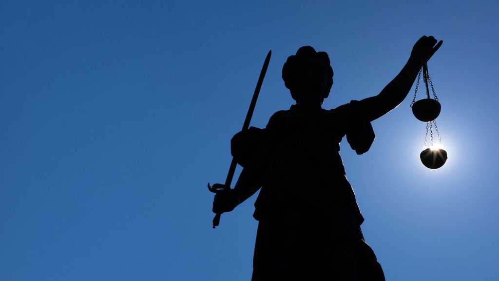 Die Silhouette der Justitia-Statue zeichnet sich gegen Sonne ab.