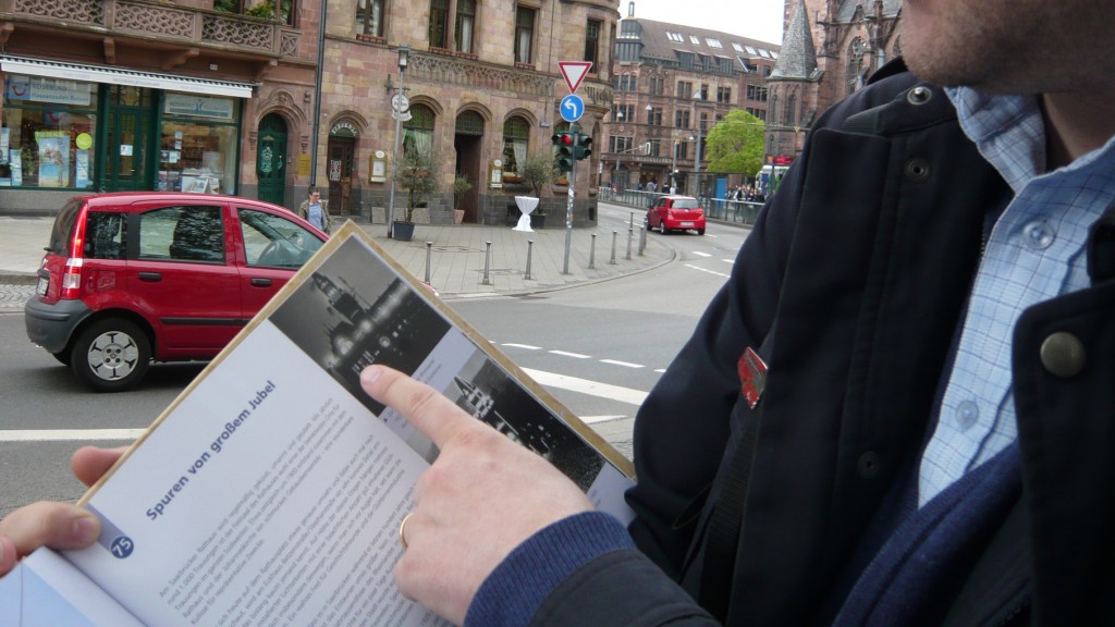Der Geograph Markus Philipp zeigt auf ein Rathaus-Foto in seinem Buch 