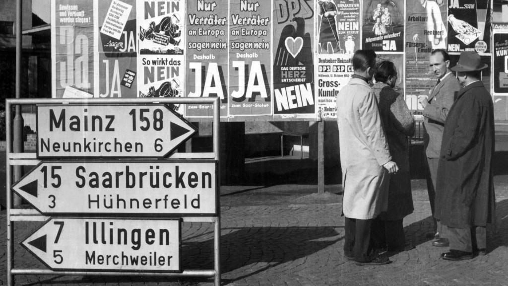 Foto: Passanten diskutieren 1955 vor einer Anschlagtafel über die bevorstehende Saarabstimmung (dpa)