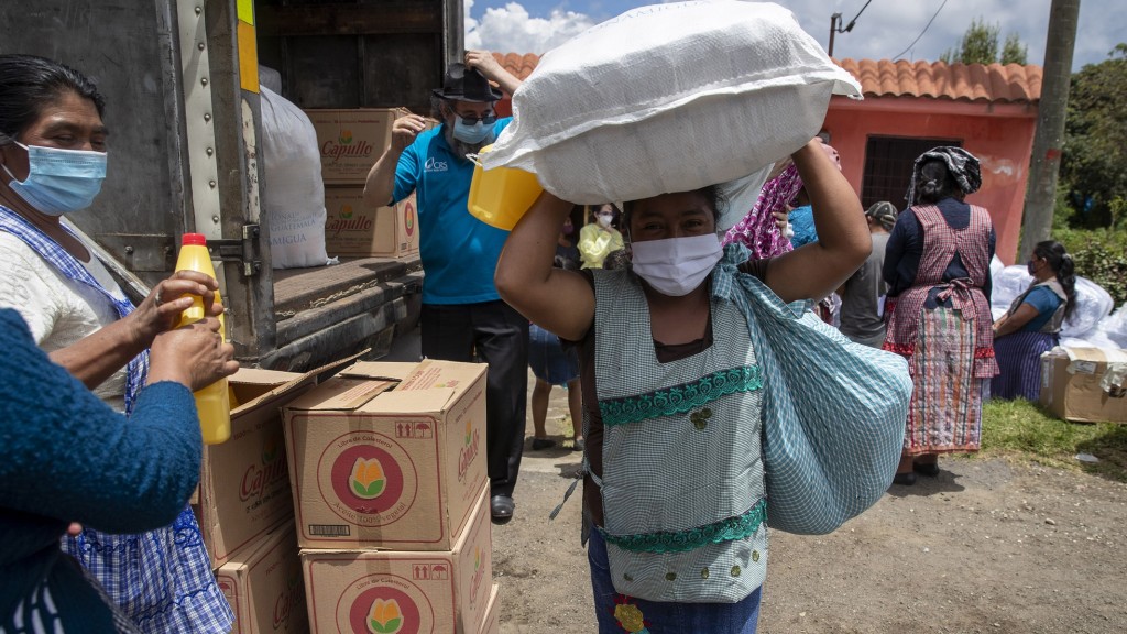 Guatemala, San Jose Calderas: eine Frau mit Mundschutz mit einem Sack voll Hilfsgütern (Foto: picture alliance/dpa/AP | Moises Castillo)