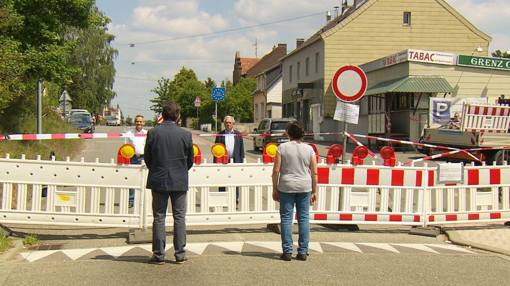 Foto: Personen vor und hinter einem provisorisch errichteten Grenzzaun zu Frankreich