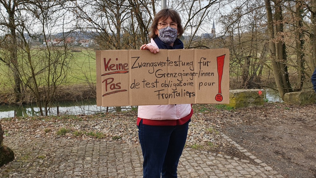Foto: Eine Frau hält ein Plakat gegen die Zwangstestung für Grenzgänger/innen in den Händen (SR/Lena Schmidtke)