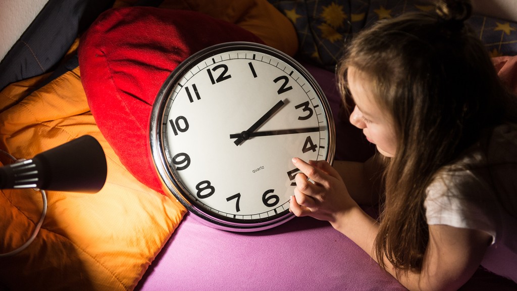 Ein Mädchen schaut in ihrem Bett auf eine Uhr. (Foto: dpa)