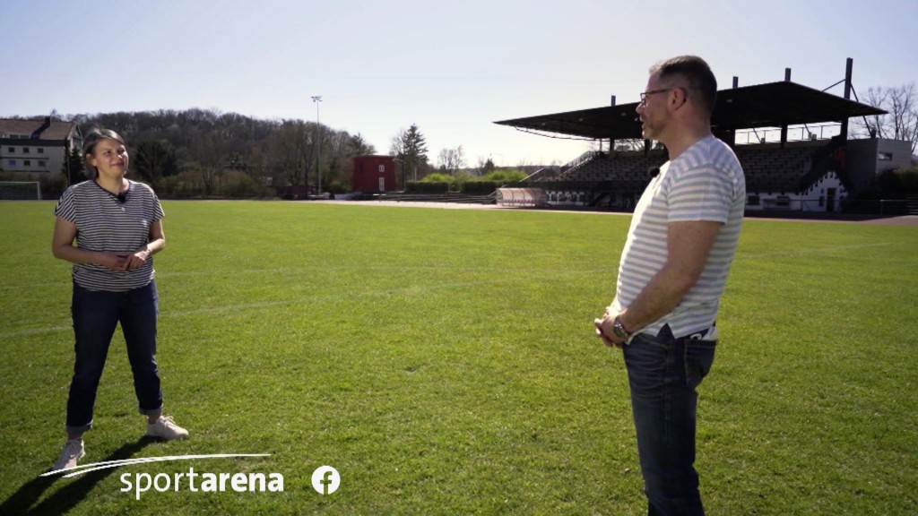 Foto: Carmen Bachmann steht mit einem Mann auf einem Fußballfeld