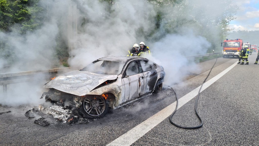 Feuerwehrmänner löschen unter schwerem Atemschutz ein brennendes Auto. (Foto: Florian Jung/Feuerwehr St. Ingbert)