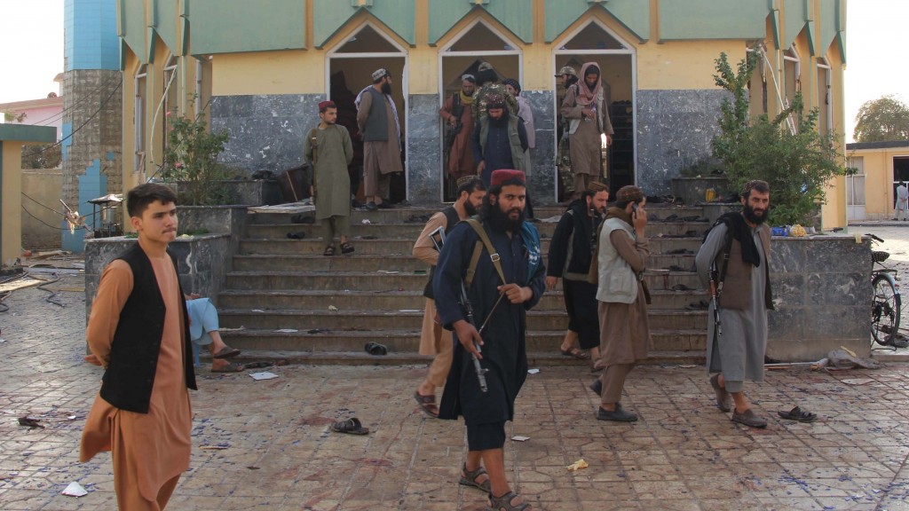 Bewaffnete Taliban-Kämpfer stehen neben einem jungen Mann vor einer Moschee in Afghanistan (Foto: picture alliance/dpa/XinHua | Ajmal Kakar)