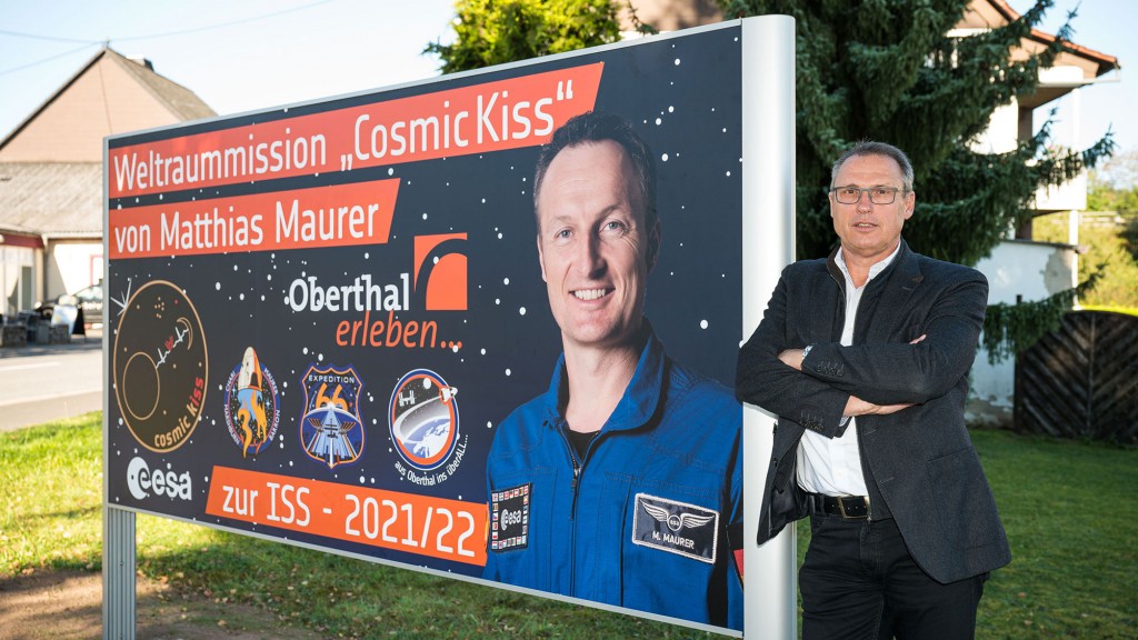 Der Oberthaler Bürgermeister Stephan Rausch neben einem Plakat zur Weltraummission von Matthias Maurer (Foto: picture alliance/dpa | Oliver Dietze) 