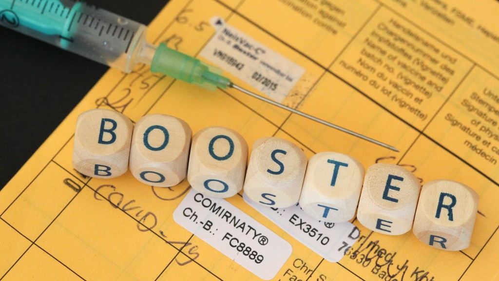 Aus einem Buchstabenspiel gebildetes Wort Booster liegt mit Impfspritze, Coronamaske, auf einem gelben Impfausweis (Foto: picture alliance / Eibner-Pressefoto | Fleig / Eibner-Pressefoto)