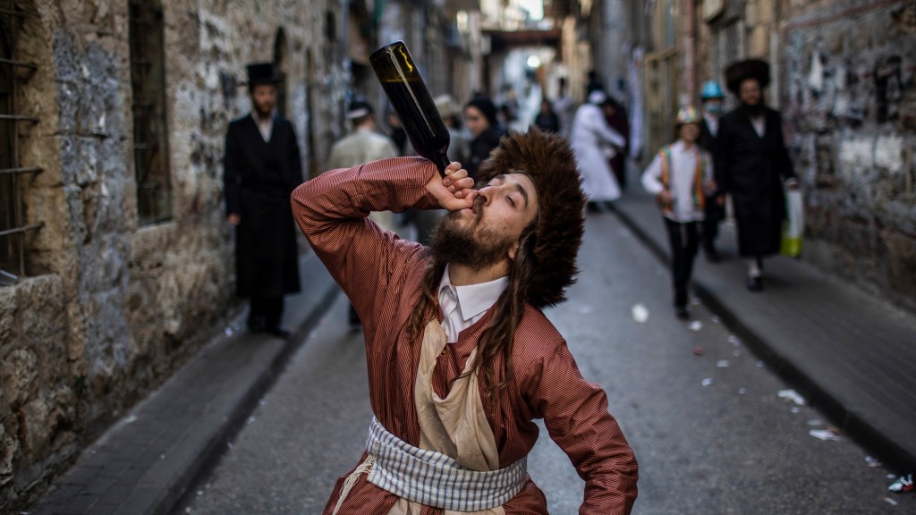 Ein ultraorthodoxer jüdischer Mann trinkt im Stadtviertel Me'a Sche'arim zu Purim aus einer Flasche (Foto: picture alliance/dpa | Ilia Yefimovich)