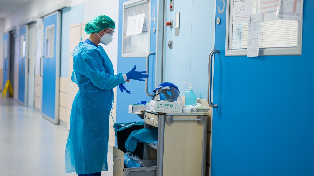 Foto: Eine Mitarbeiterin im Krankenhaus legt Schutzkleidung an. (Foto: picture alliance/dpa | Oliver Dietze)