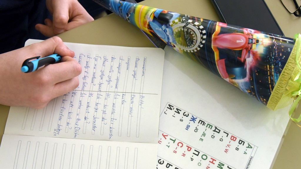Foto: Ein Junge aus der Ukraine schreibt im Deutschunterricht Vokabeln in sein Heft. Daneben liegt eine kleine Zuckertüte, die er am ersten Schultag zur Begrüßung erhalten hat. (Foto: picture alliance/dpa/dpa-Zentralbild | Waltraud Grubitzsch)