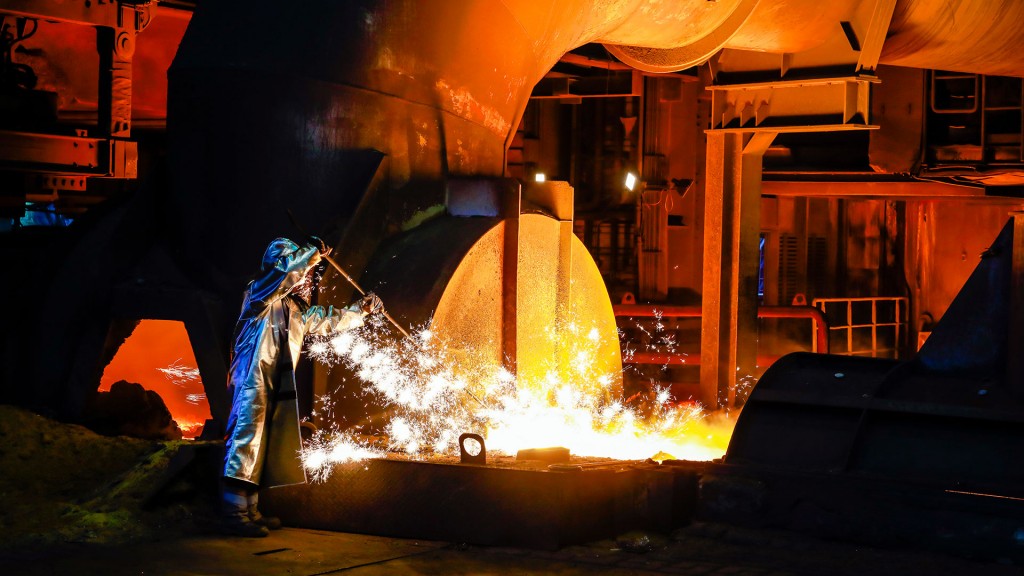 Stahlproduktion – ein Stahlarbeiter im Schutzanzug entnimmt eine 1500 Grad heisse Roheisenprobe beim Abstich am Hochofen