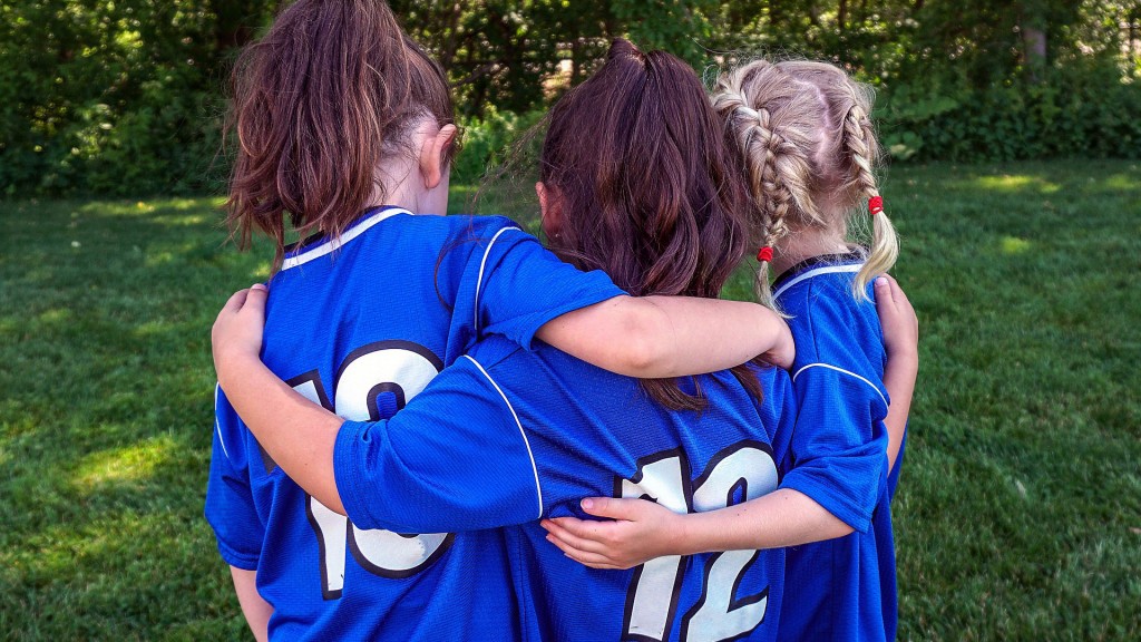 Drei Mädchen im Fußballtrikot umarmen sich