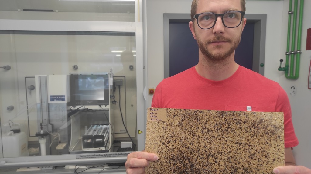 Ein Forscher hält eine Platte gepressten Treber