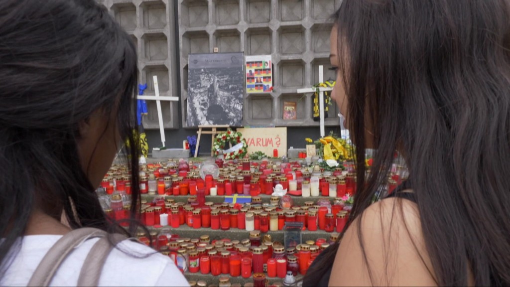 Foto: Zwei Mädchen vor einer Trauerwand mit Kerzen