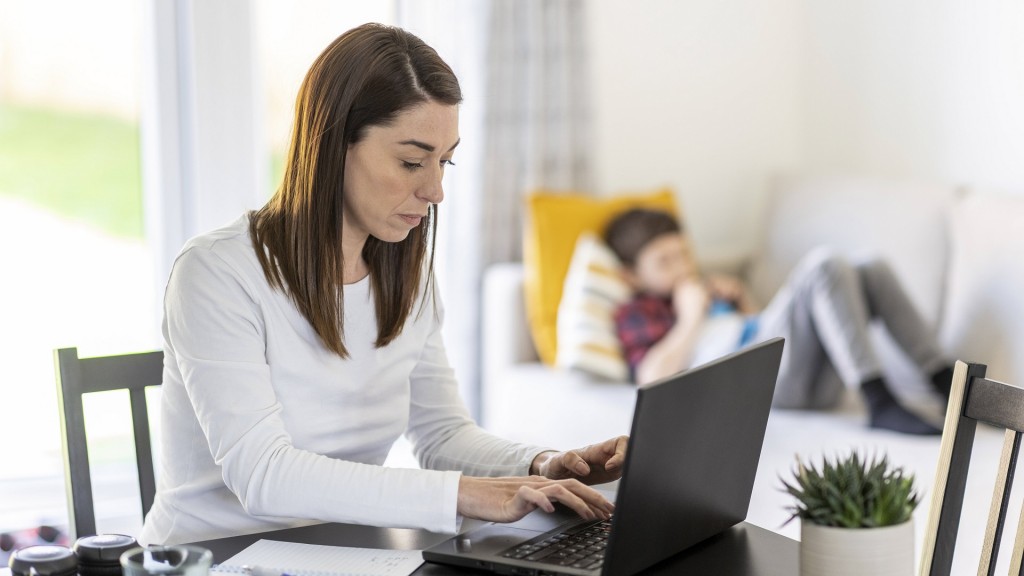 Eine Frau arbeitet am Laptop während ihr Kind im Hintergrund ist.
