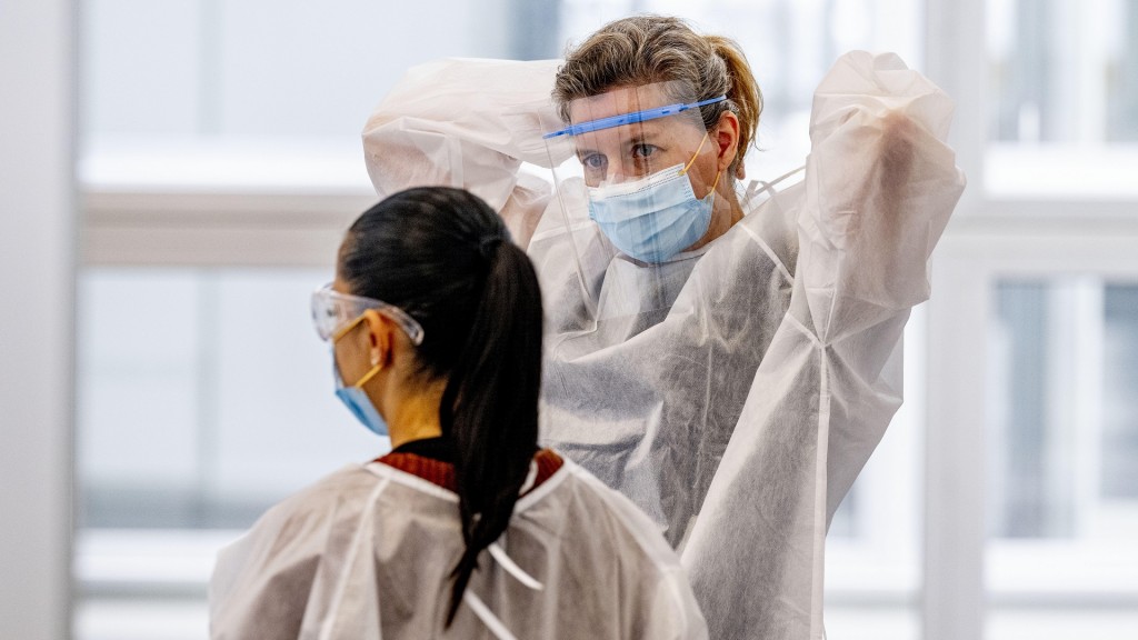 Zwei Frauen in Schutzanzügen mit Maske und Augenschutz