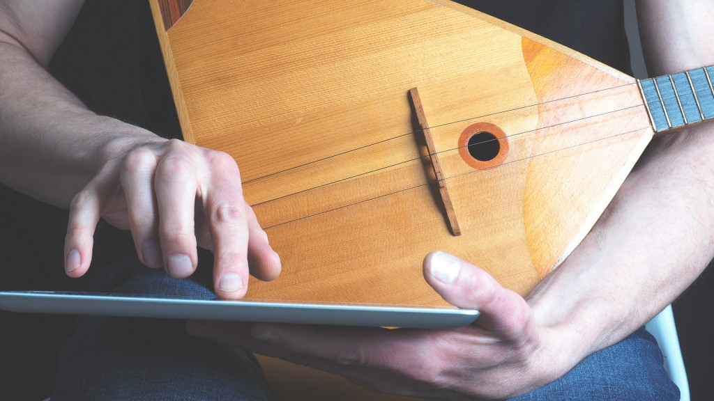 Symbolbild: Ein junger Musiker lernt Balalaika per App auf dem Tablet