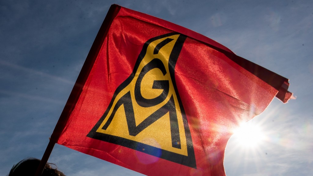 Teilnehmer einer Kundgebung halten eine Fahne mit dem Logo der IG Metall hoch.