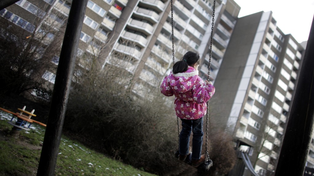 Foto: Ein Kind schaukelt auf einem Spielplatz vor einem Hochhaus