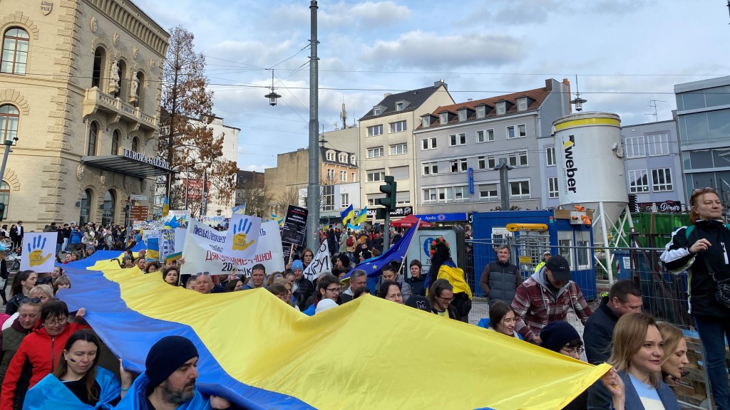 Demonstrierende mit einer großen Flagge der Ukraine