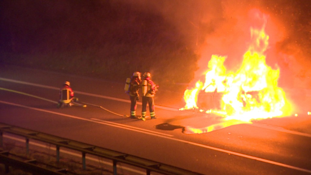 Feuerwehrleute löschen ein brennendes Auto