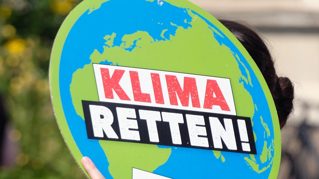 Eine Frau trägt eine Schild in Form der Weltkugel, mit der Aufschrift 