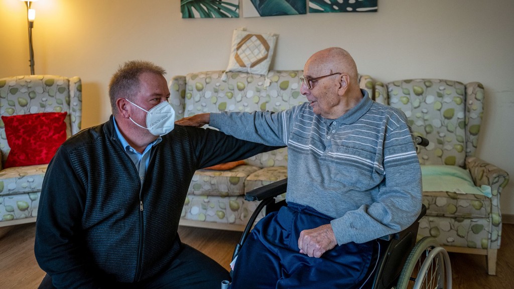 Foto: Ein Besucher mit Maske und ein Bewohner ohne im Pflegeheim