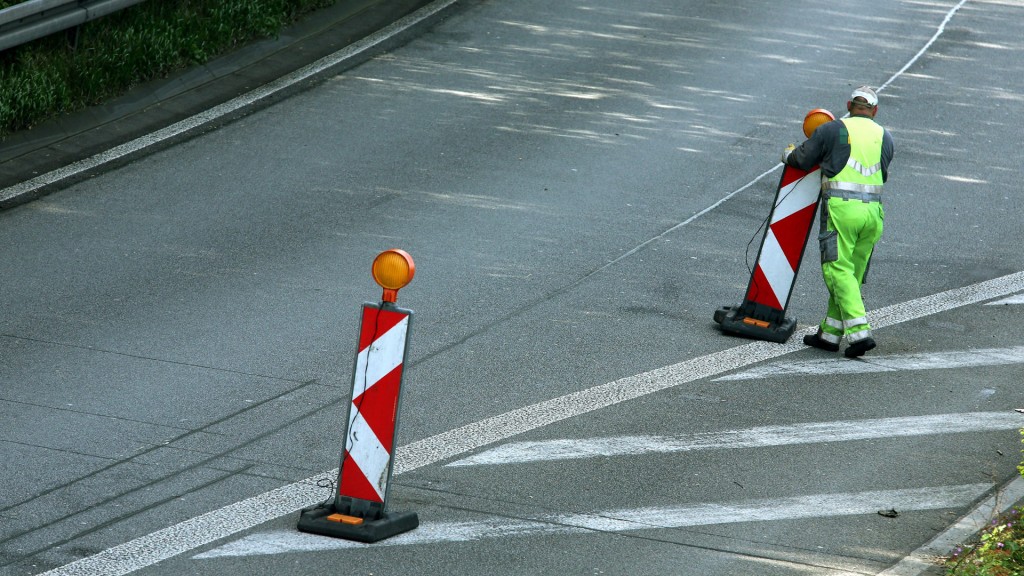 Ein Arbeiter schiebt Warnbarken auf die Straße.