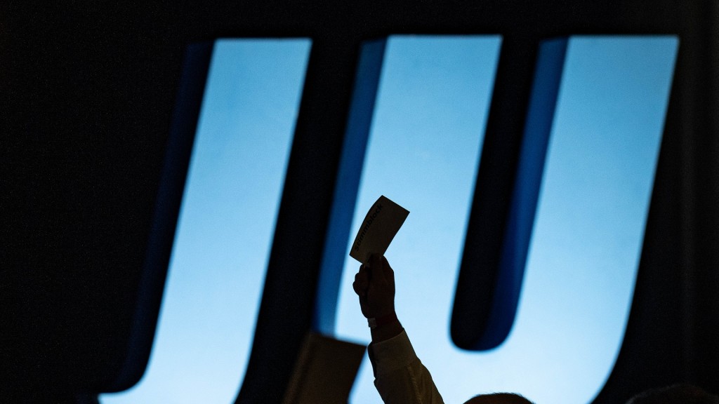 Delegierte heben auf einer Landesversammlung Union vor dem Logo der JU ihre Stimmkarten