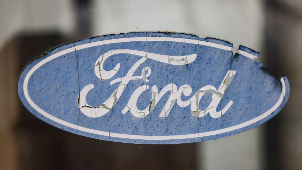 Foto: Ein abgeblättertes Logo von Ford hängt an einer Scheibe vor dem Werksgelände.