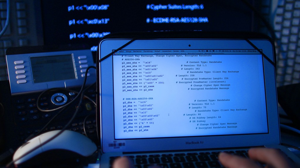 Ein Mann sitzt vor einem Rechner, auf dessen Bildschirm ein Computer Quellcode zu sehen ist.