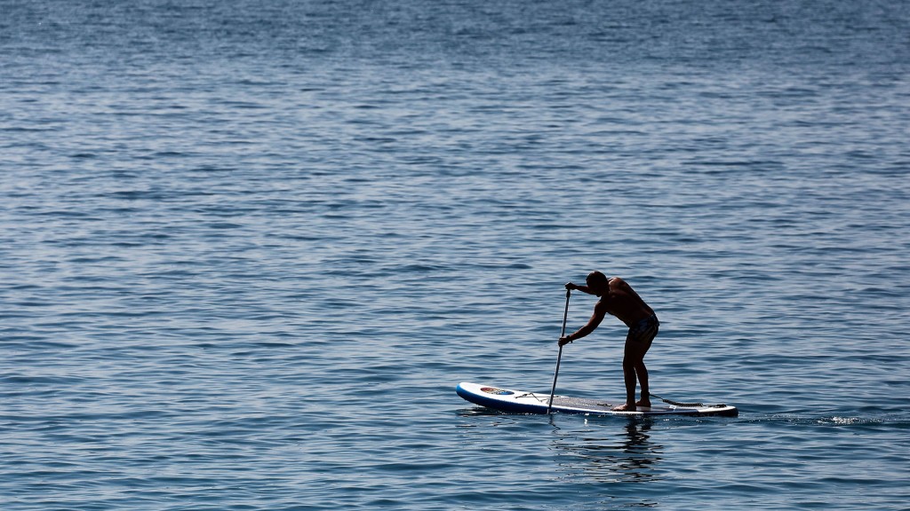 Foto: Ein Mann fährt auf einem Stand-up-paddle-board über das Wasser