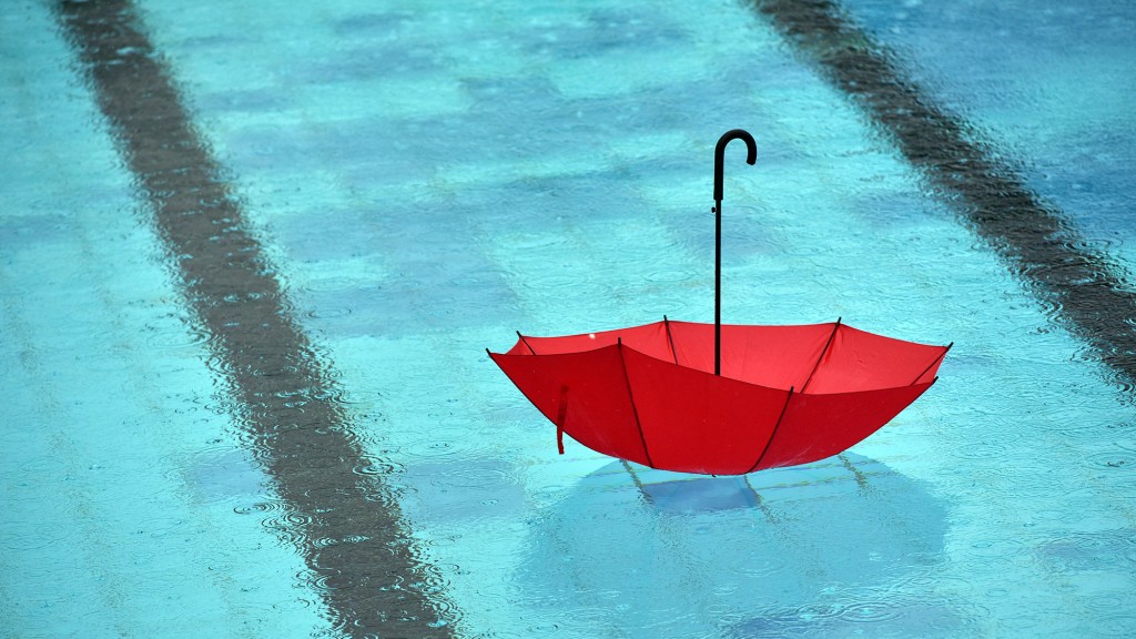 Bei Regen schwimmt ein Regenschirm in einem Freibad-Becken