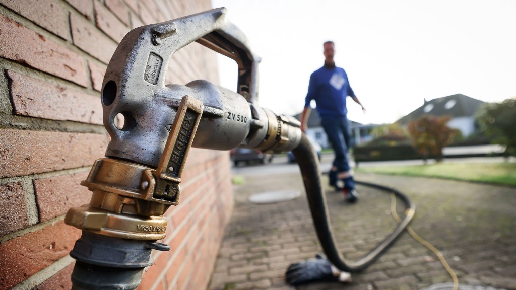 Ein Mitarbeiter eines Diesel- und Heizöl-Unternehmens geht zur Zapfpistole an einem Füllstutzen für die Heizöllieferung an einen Kunden in einem Einfamilienhaus