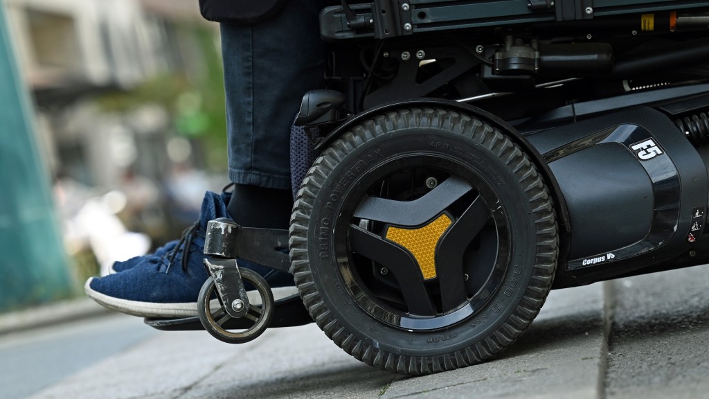 Foto: Ein Mann fährt in seinem elektrischen Rollstuhl über eine Straße.