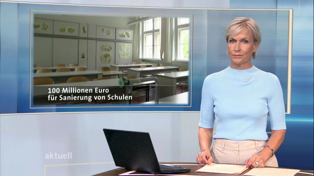 Foto: Moderatorin Verena Bisle neben Bildtafel