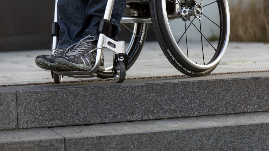 Foto: Ein Rollstuhlfahrer steht in seinem Rollstuhl an einer Treppe vor einem Gebäude.