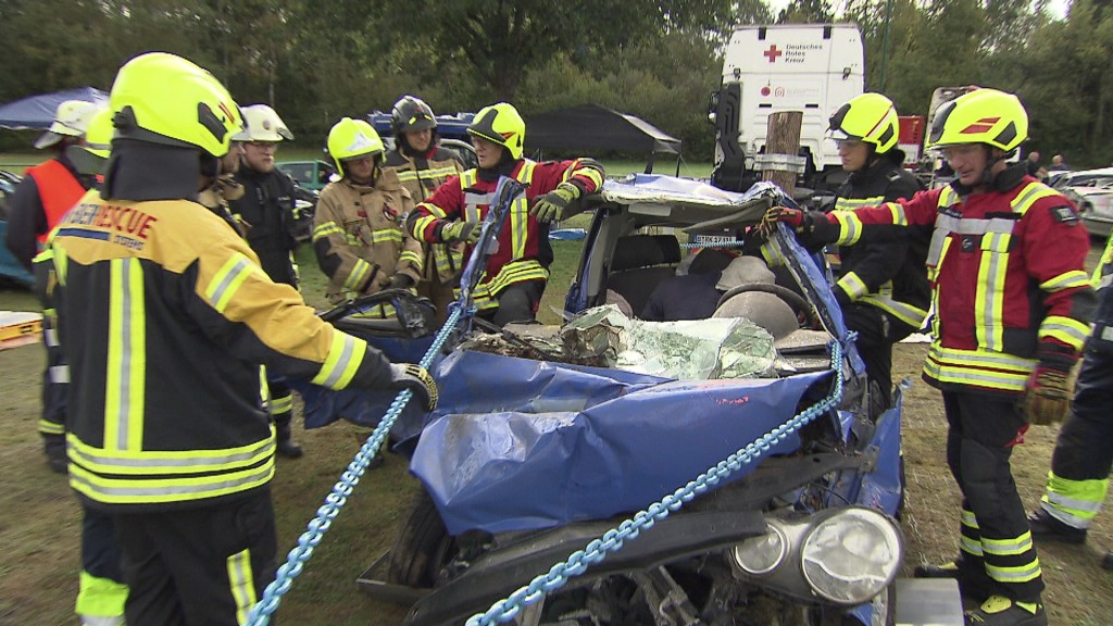 Foto: Einsatzkräfte mit einem zerstörten Auto