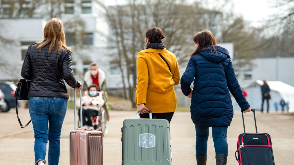 Drei aus der Ukraine stammende Frauen gehen mit ihren Habseligkeiten in Koffern zu ihrem Quartier