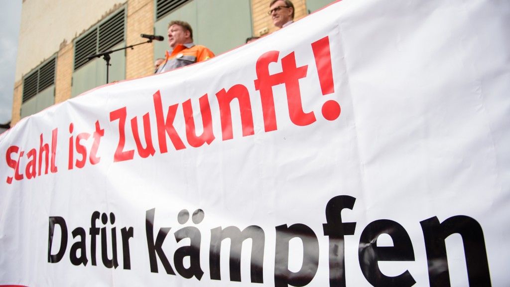 Mit einem Banner protestieren Mitarbeiter der Stahlindustrie