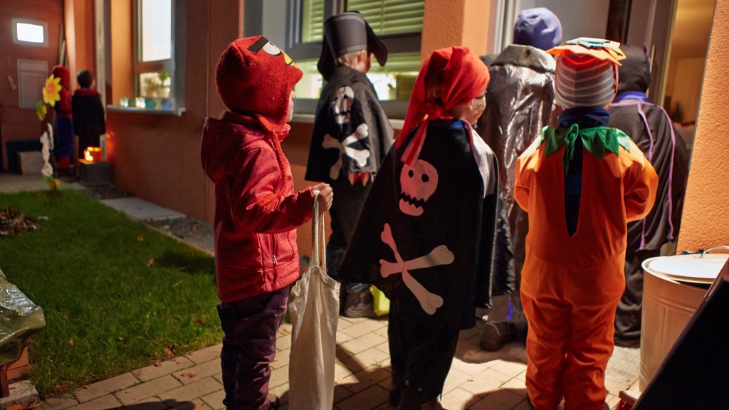 Kinder in Halloween-Kostümen sammeln am 31.10. an einer Haustür Süßigkeiten.
