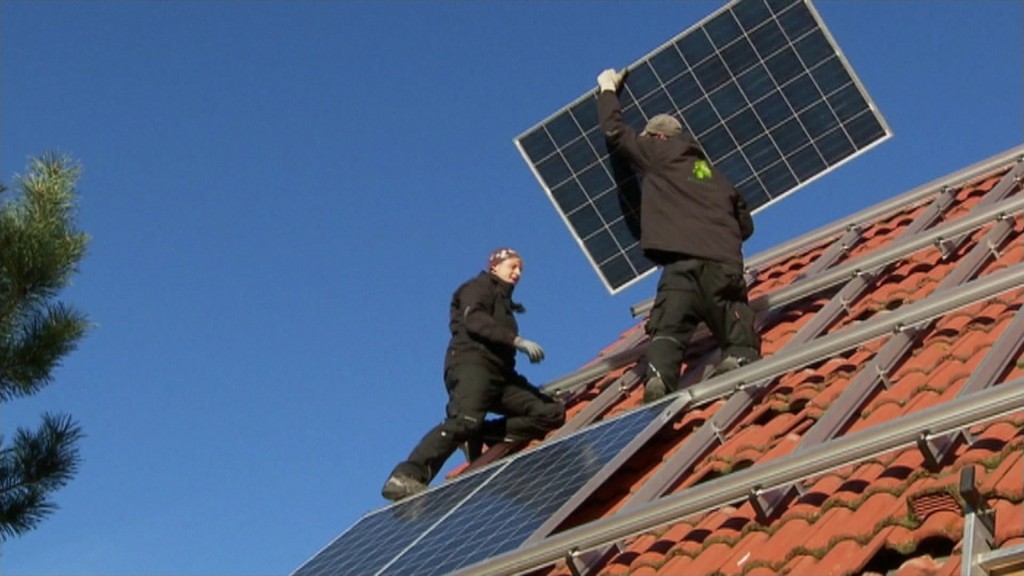 Foto: Zwei Handwerker decken ein Dach mit Solarzellen ein