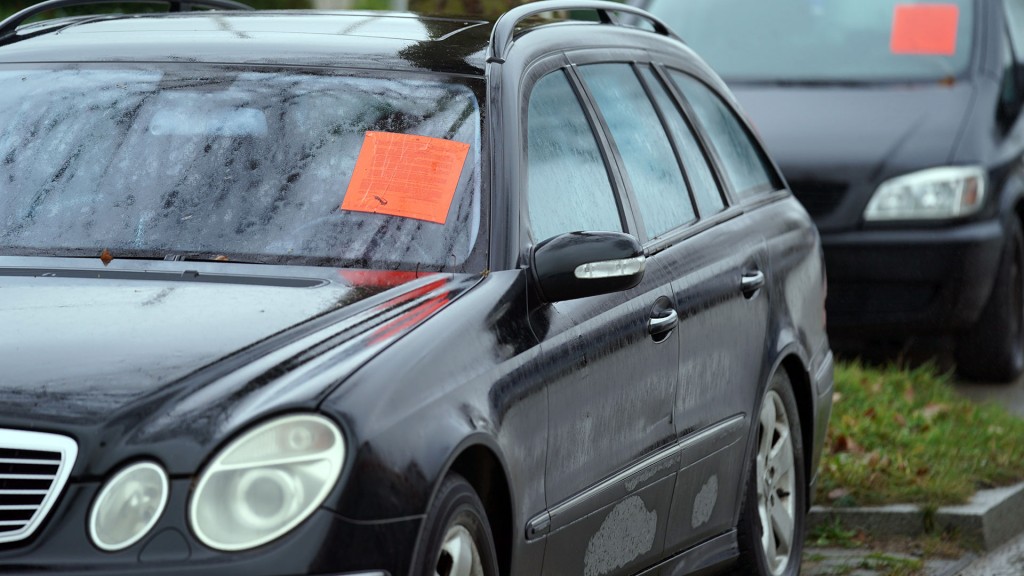 Rote Hinweiszettel kleben auf den Windschutzscheiben unrechtmäßig abgestellter Fahrzeuge am Straßenrand