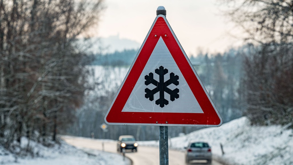 Foto: Ein Verkehrsschild mit einer Schneeflocke, das vor glatter Fahrbahn warnt steht am Straßenrand