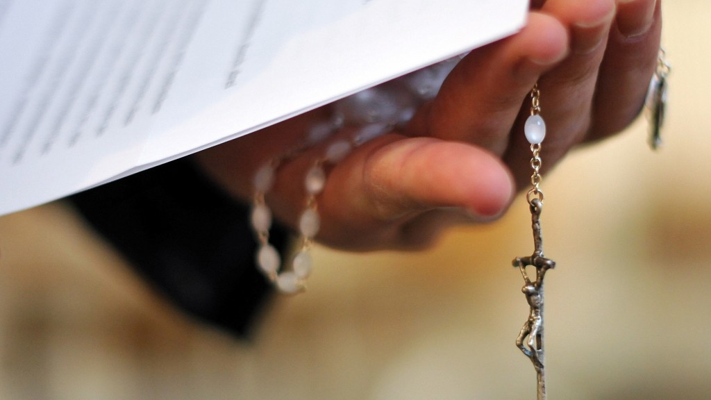 Ein Priester hält einen Rosenkranz