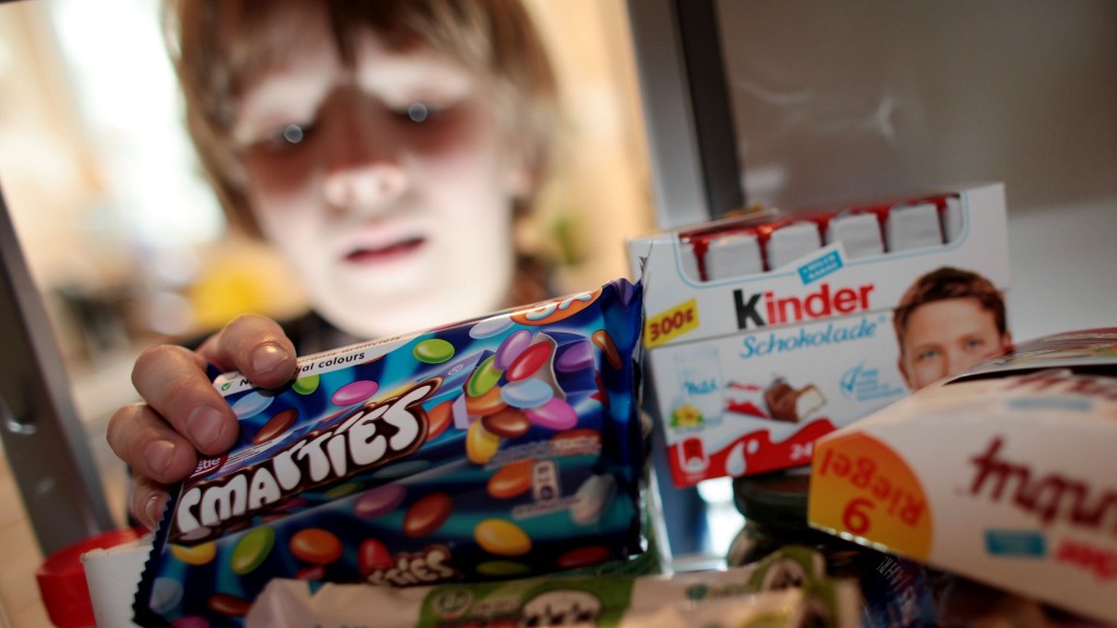 Ein Junge nimmt Süßigkeiten aus dem Schrank. 